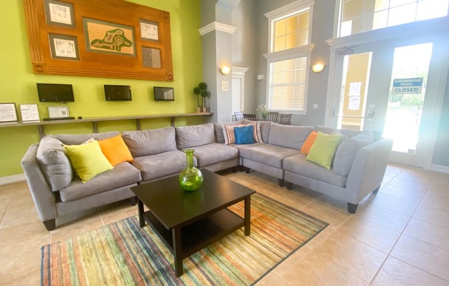 Clubhouse lounge with couch, coffee table, tiled flooring, and floor rug