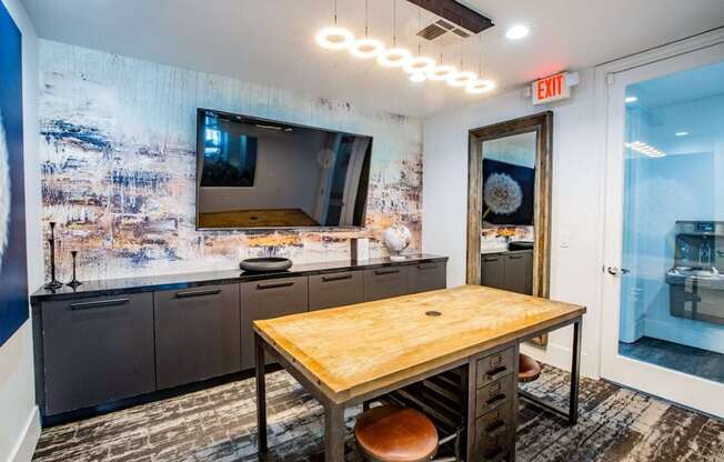 Colton Apartments A room with a wooden table and a large TV on the wall.