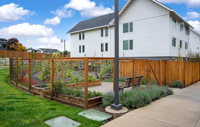 a garden with a wooden fence in front of a house