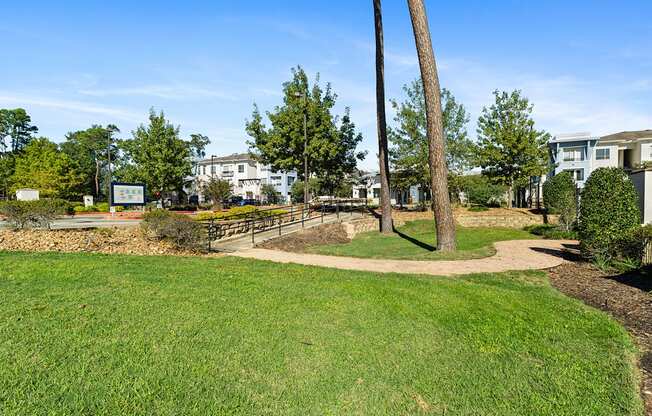 A grassy area with a tree and a sign in the background.