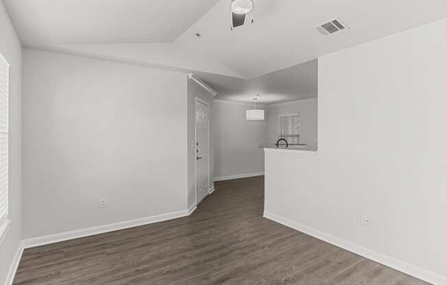 an empty living room and kitchen with white walls and wood flooring