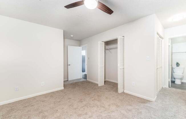 an empty living room with a ceiling fan and a bathroom