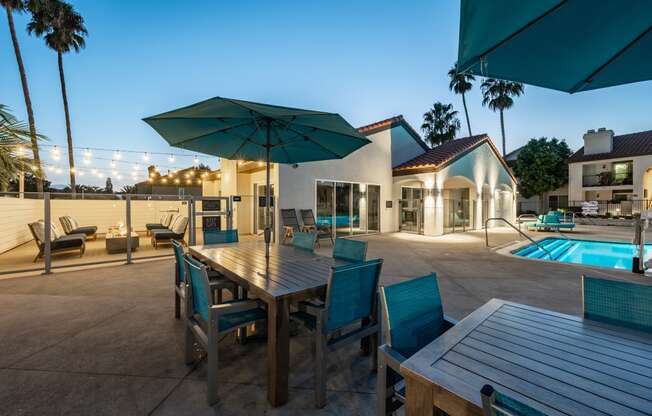 a dining table with chairs and umbrellas next to a pool at Laguna Gardens Apts., California, 92677