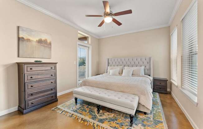 A bedroom with a large bed, a dresser, and a ceiling fan. at Bridge at Heritage Woods, Austin, Texas