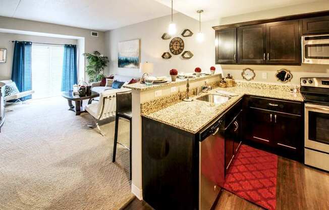 A kitchen with dark cabinets and view of the living room