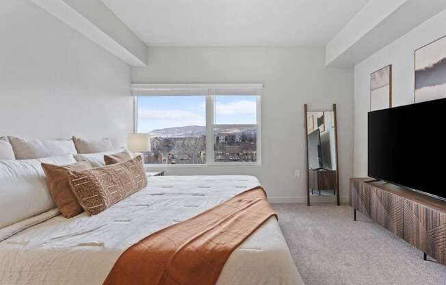 A bedroom with a large bed and a flat screen TV at Wilmington Flats Apartments, Utah, 84106