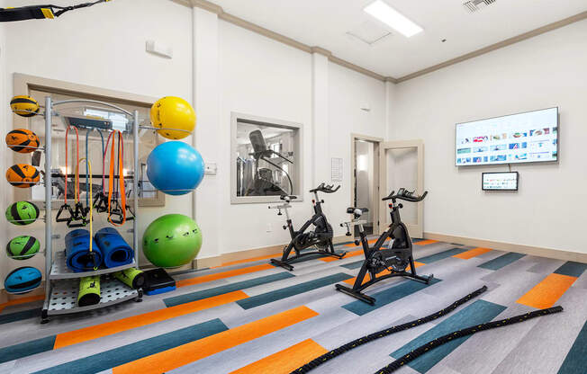 A gym with exercise equipment and a TV screen.