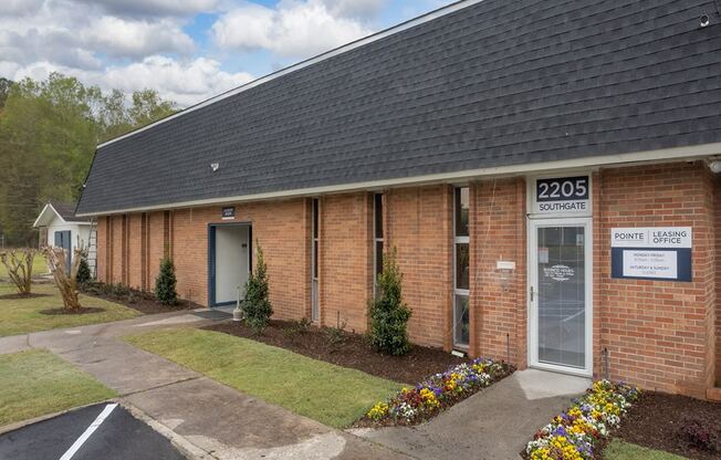 the front of a brick building with a sidewalk and grass