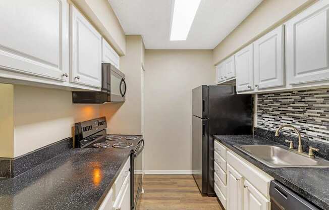 A kitchen with black appliances and white cabinets.