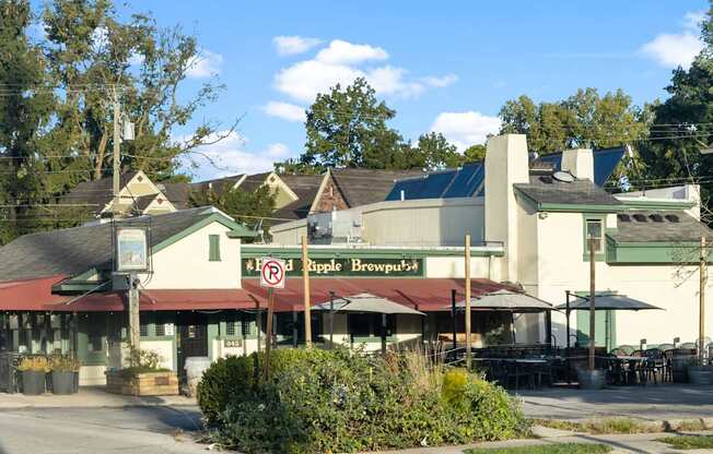 a restaurant with tables and umbrellas in front of a building