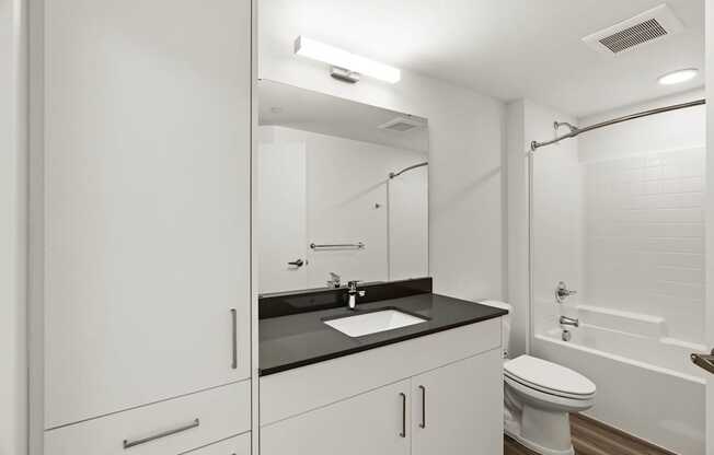 A white bathroom with a sink, toilet, and bathtub.