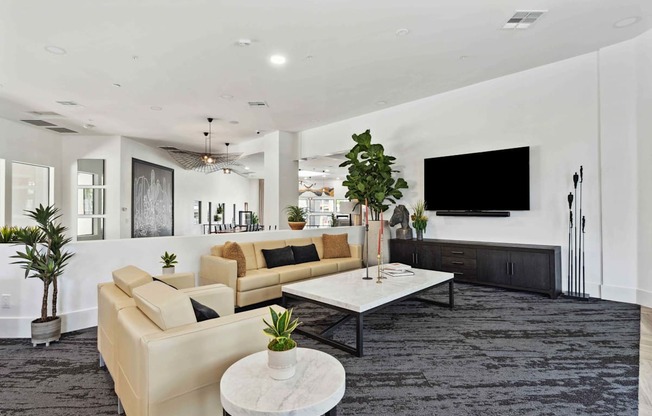 A modern living room with a large couch, a coffee table, and a flat-screen TV.