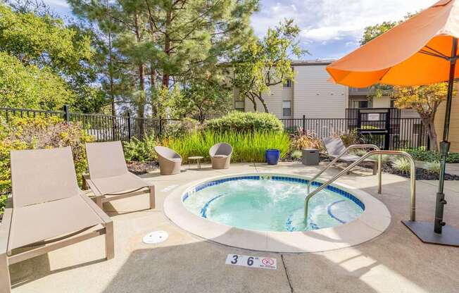 A small pool surrounded by a concrete patio and a black fence.