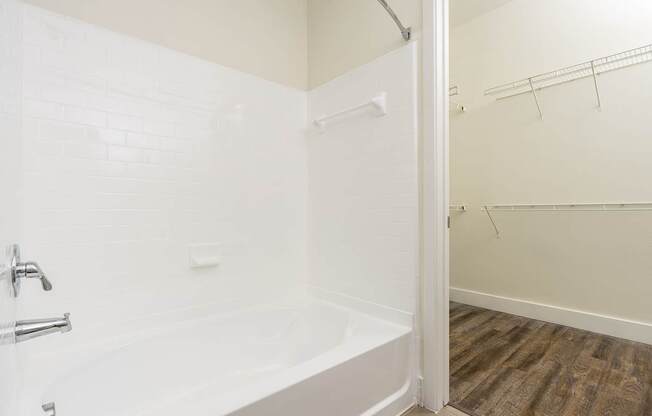 A white bathroom with a tub and a wooden floor.