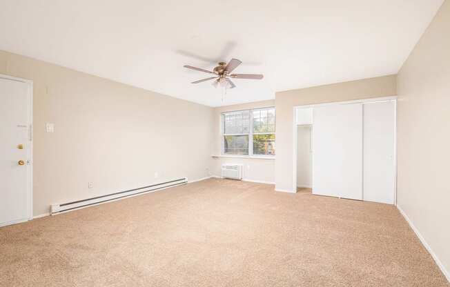 an empty living room with a ceiling fan