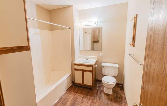 A small bathroom with a toilet, sink, and shower.