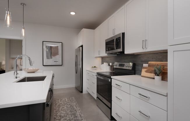 an open kitchen with white cabinets and black appliances and a sink