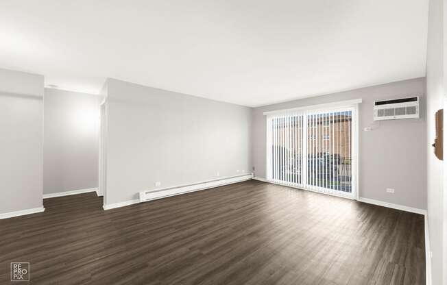 an empty living room with wood floors and a window