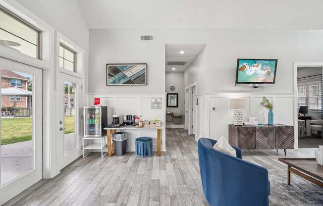 A blue chair is in the foreground of a well-lit, modern living room.