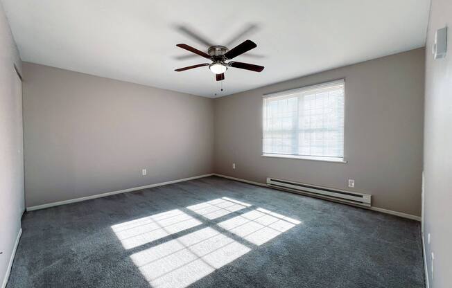 an empty room with a ceiling fan and a window