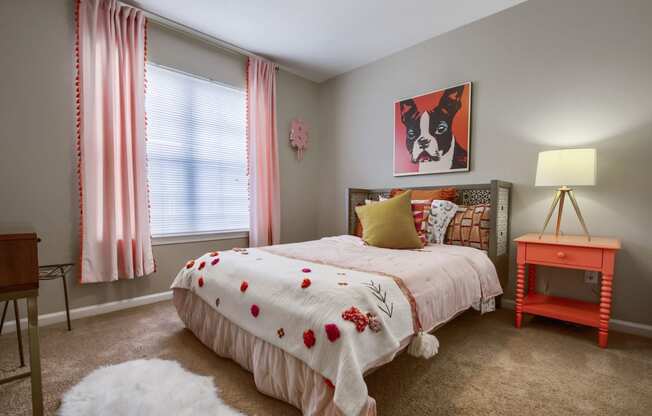 a bedroom with a bed and a nightstand with a lamp and a painting of a dog