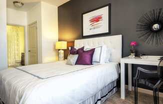 A bedroom with a white bed and a black chair.
