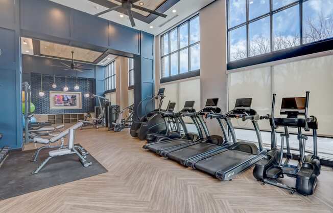 a gym with treadmills and weights and windows