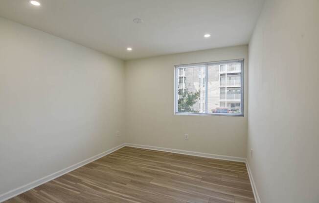 Empty room with wooden flooring and a window.