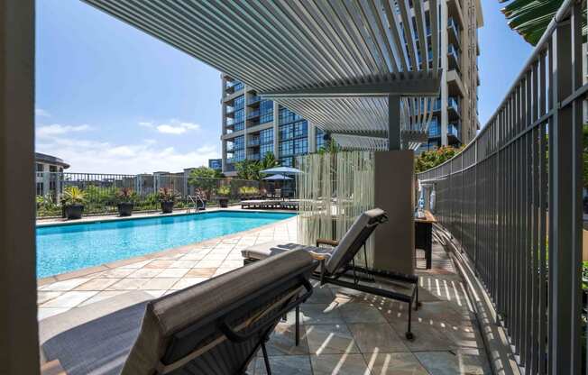 Irvine, CA, Apartments for Rent - Astoria at Central Park West - Gated Pool with Lounge Chairs, Umbrellas, and Potted Plants.