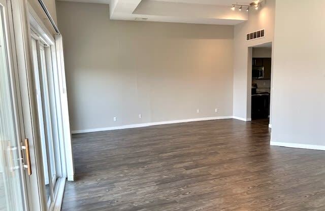 an empty living room with wood flooring and white walls