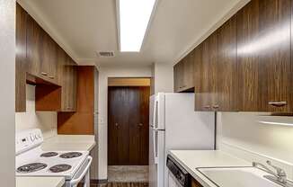 A kitchen with white appliances and wooden cabinets.