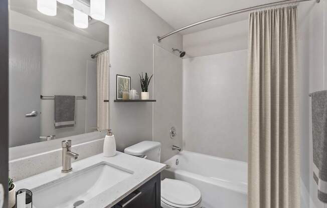 A modern bathroom with a white sink, toilet, and bathtub.