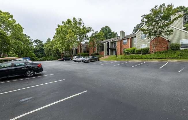 an empty parking lot in front of apartment buildings with cars parked on the street