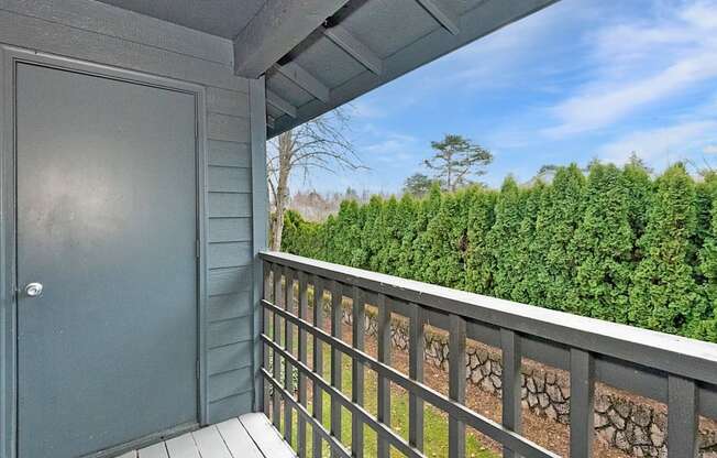 A view from a balcony with a grey door and a stone wall.