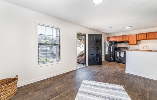 a living room and kitchen with a large window and a door