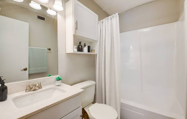 a bathroom with a white shower and toilet next to a sink and mirror