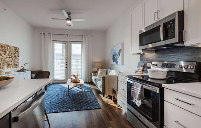 a kitchen and living room with a stove and a microwave