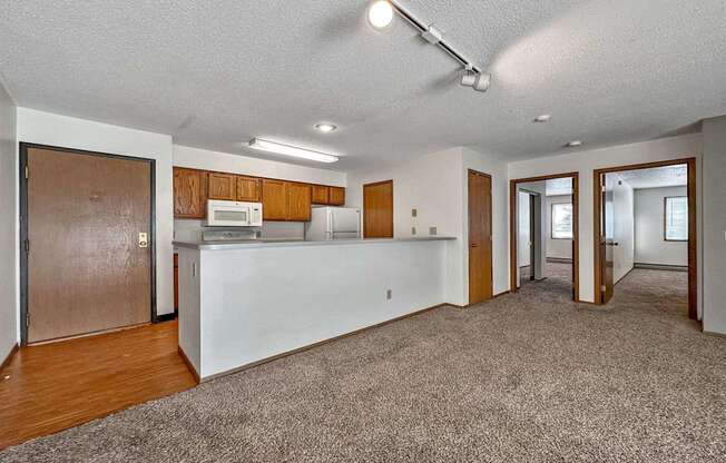 an empty living room with a kitchen with a counter top