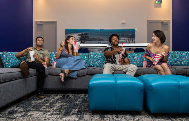 Three people are sitting on a couch eating popcorn and watching television.at Icon One, Florida, 32114