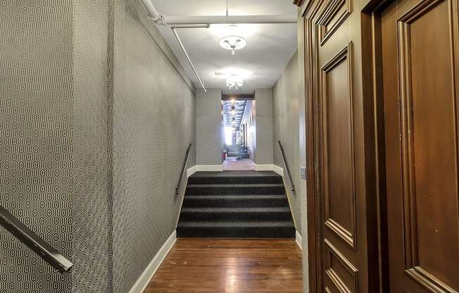 a long hallway with stairs and wood flooring and a hallway with doors and stairs at The Knights @ 506 Delaware Apartments, Buffalo, 14202