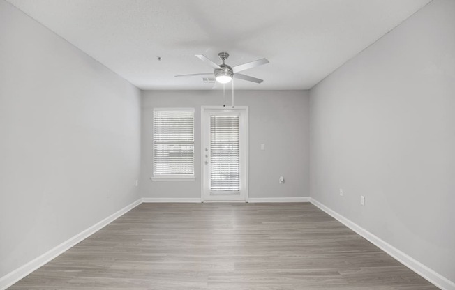 an empty living room with white walls and a ceiling fan