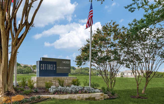 A sign for Cottages at Millers Point stands in front of a grassy field.