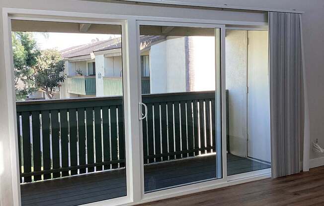 A sliding glass door with a white frame and a balcony with a black railing.