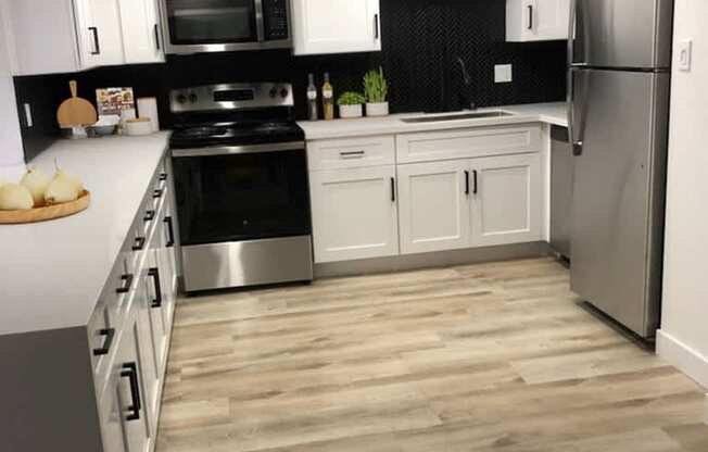 A kitchen with white cabinets and a black backsplash.
