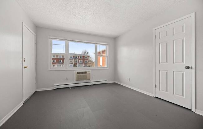 A room with a large window and a view of a building outside.