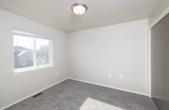 A room with a window and a carpet on the floor.