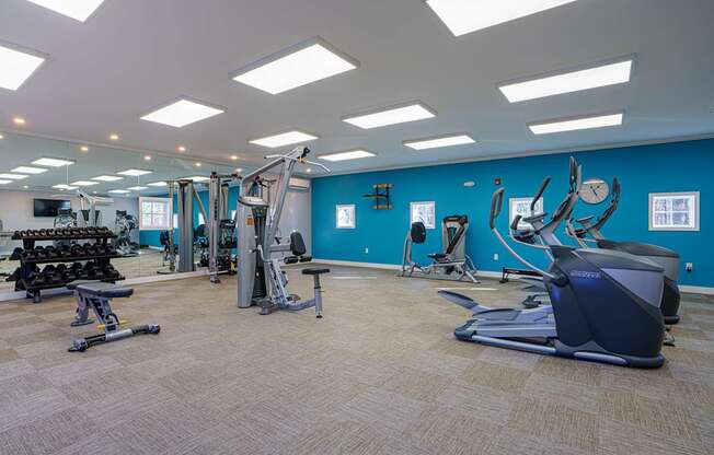A gym with a variety of equipment including treadmills, weights, and exercise machines.
