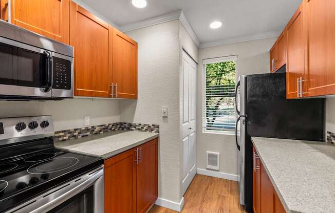 A kitchen with wooden cabinets and a black refrigerator.