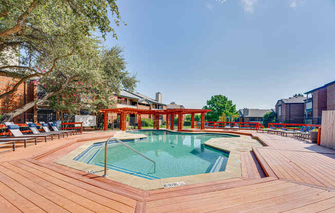 a swimming pool with a wooden deck with chairs around it