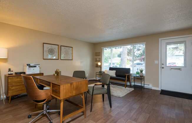 Pinewood Terrace Apartments | Leasing Office Model showing entrance, office desk, three chairs and a sitting couch.